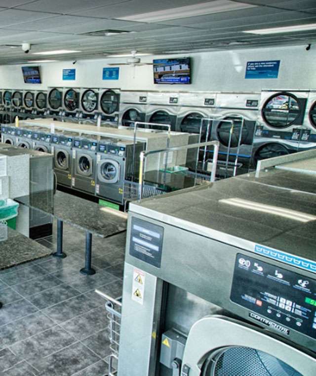 Granite folding stations running down the middle of the floor, with dryers and wall televisions behind